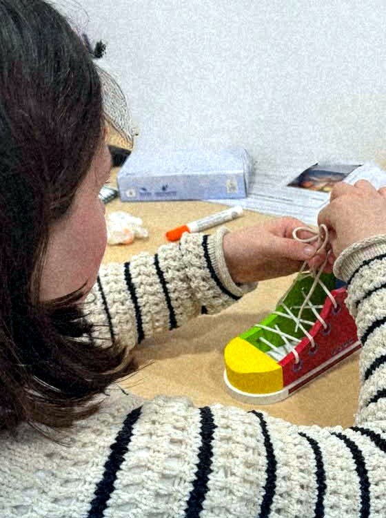 Una persona practica a atarse los cordones en un zapato de entrenamiento durante una sesión de terapia ocupacional